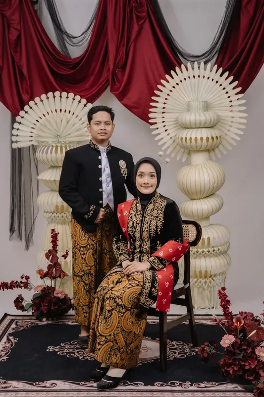 Mempelai wanita duduk dengan mempelai pria berdiri di sisinya
